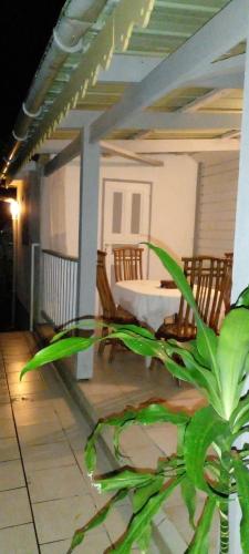 eine Veranda mit einem Tisch, Stühlen und einer Pflanze in der Unterkunft La Creoline 01 in Pointe-Noire