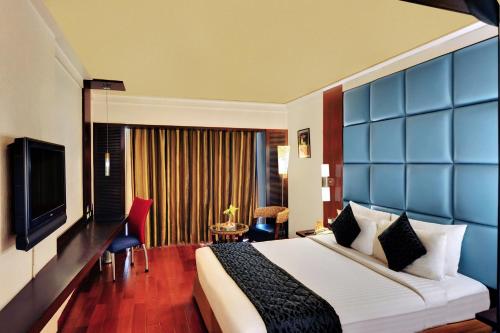 a hotel room with a bed and a television at Iris The Business Hotel in Bengaluru
