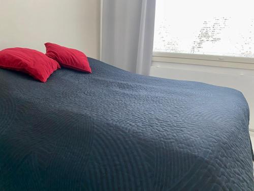 een blauw bed met twee rode kussens in een slaapkamer bij Huttunen - Ihqu kolmio loistavalla sijainnilla in Iisalmi