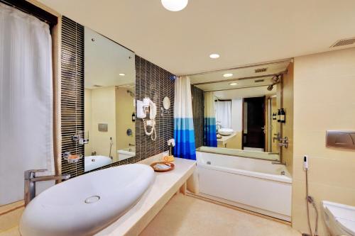 baño con bañera blanca grande y lavamanos en Iris The Business Hotel, en Bangalore