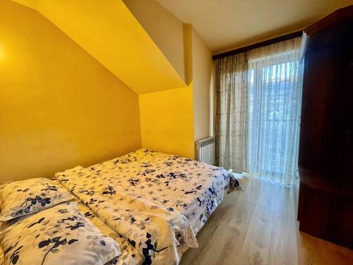 a bedroom with a bed with a yellow wall and a window at Holiday Home 36 in Tsaghkadzor