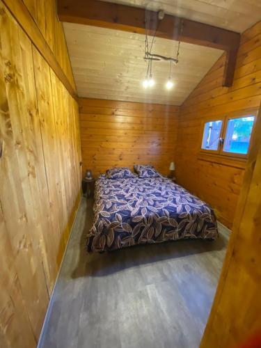 una camera da letto con letto in una camera in legno di Le petit chalet du mouralet a Légna