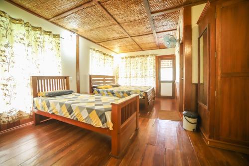 Habitación con 2 camas, suelo de madera y ventanas. en Xplore Indo - Glamping Villa, en Napoklu
