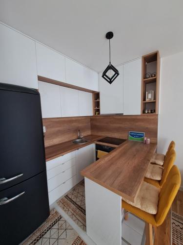 a kitchen with a wooden table and a black refrigerator at Stan na dan Iv in Lukavica
