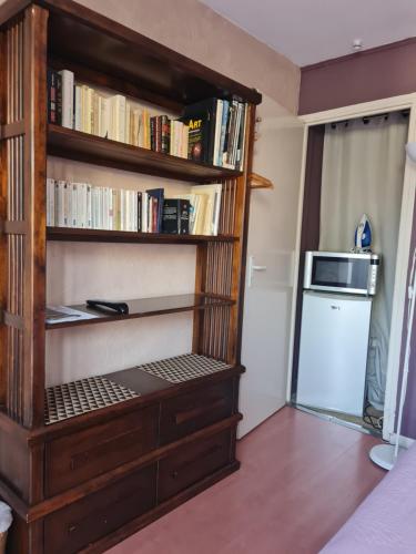 a book shelf with a microwave and a refrigerator at Chez Hélène in Bordeaux
