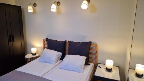a bedroom with a bed with two pillows and two lights at TyzenXL Luxury Vilnius Apartments in Vilnius