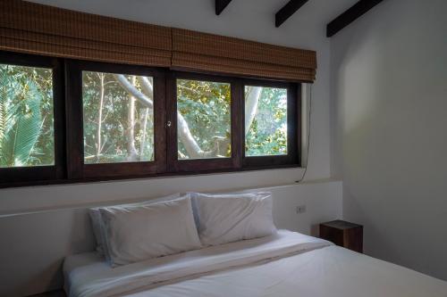 a bed with two pillows in a room with windows at Lunar Villas Koh Tao - Luxury Private Pool Villas in Ko Tao