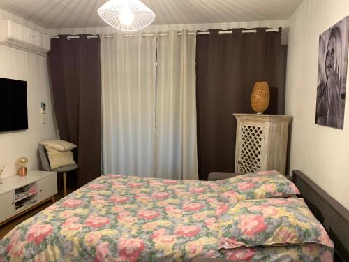 una camera da letto con un letto con copriletto floreale di Appartement rue de l'amarrage à PORT GRIMAUD avec Terrasse vue canaux et garage a Grimaud