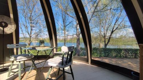 Habitación con mesa, 2 sillas y ventana grande. en Bulle de l'étang - Etat Nature en Magnières