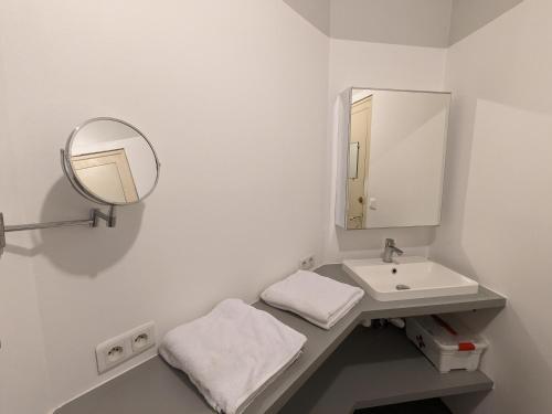 a white bathroom with a sink and a mirror at Hyper Centre La Roche sur Yon - Appartement spacieux et lumineux in La Roche-sur-Yon