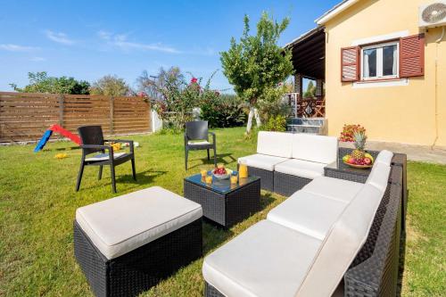 a backyard with a white couch and chairs at Villa Marietta in Agios Gordios