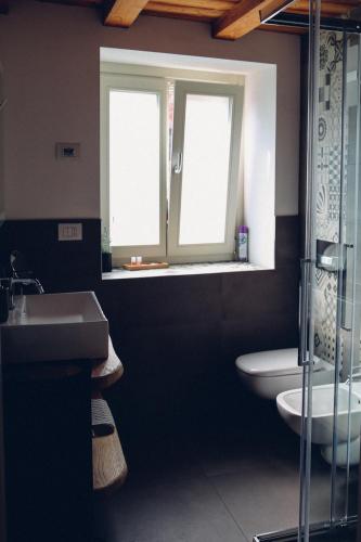 a bathroom with a sink and a toilet and a window at Aosta Romana case vacanza in Aosta