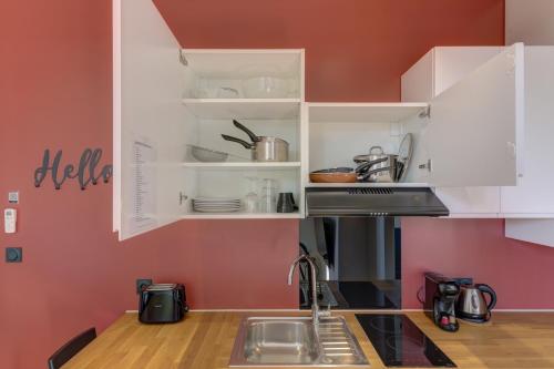 a kitchen with pink walls and white cabinets at Terracotta-T2-Clim-Parking gratuit privé in Pierre-Bénite