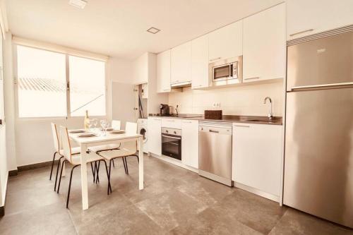 a kitchen with white cabinets and a table with chairs at Torre de la Vela 2 in Granada