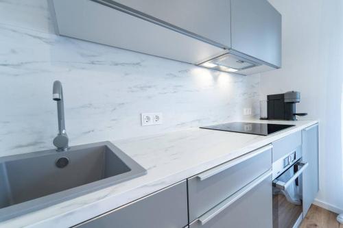 a white kitchen with a sink and a counter at Apartment mit Schwimmbad und Privatparkplatz in Augsburg