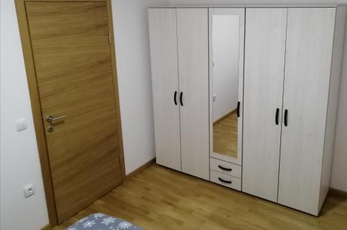 een slaapkamer met witte kasten en een spiegel bij APARTMAN STEP WAy in Vrbas