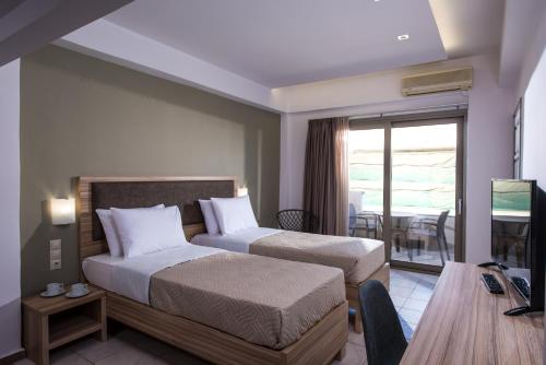 a hotel room with two beds and a balcony at Thania Seaside Smotel - Adults Only in Agia Pelagia