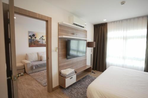 a hotel room with a bed and a flat screen tv at Calypso Condo Rawai Nai Harn beach in Rawai Beach