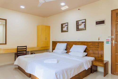 a bedroom with a large white bed with a wooden headboard at MEHEL - Holiday Home - Mahibadhoo in Mahibadhoo