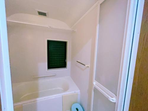 a white bathroom with a tub and a shower at Miyama House in Hachioji