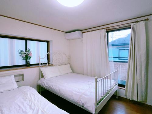een kleine slaapkamer met 2 bedden en een raam bij Miyama House in Hachioji