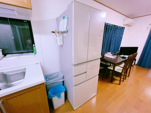 a kitchen with a white refrigerator next to a table at Miyama House in Hachioji