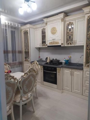 eine Küche mit weißen Schränken sowie einem Tisch und Stühlen in der Unterkunft 1комнатная квартира in Bischkek