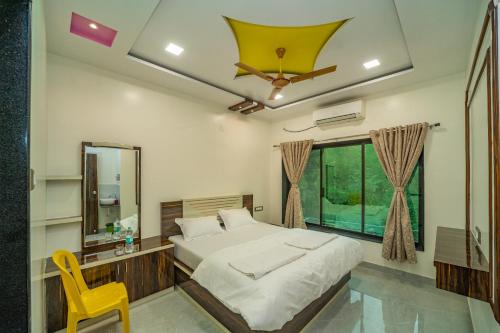 a bedroom with a bed and a mirror and a yellow chair at Happy Stay Villa - Kashid beach in Kashid