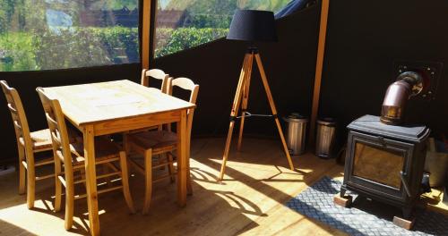 une table et des chaises dans une pièce avec une table en bois et une caméra dans l'établissement Bulle forestière - Etat Nature, à Magnières