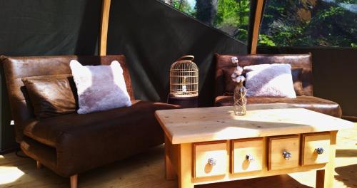 - un salon avec deux chaises, une table et une cage pour oiseaux dans l'établissement Bulle forestière - Etat Nature, à Magnières