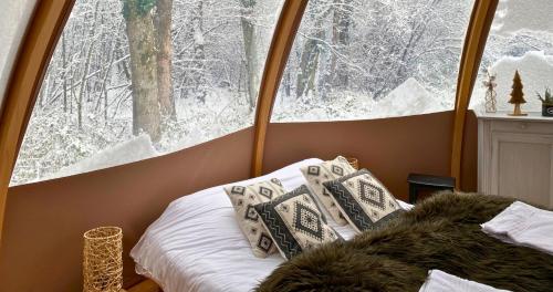 sypialnia z łóżkiem i oknem ze śniegiem w obiekcie Bulle forestière - Etat Nature w mieście Magnières