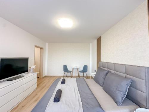 a room with a bed and a television and chairs at Apartmán Simcity Bratislava in Bratislava