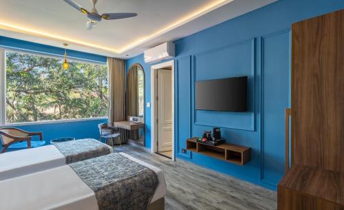 a hotel room with blue walls and a tv at Renest Calangute Goa in Calangute