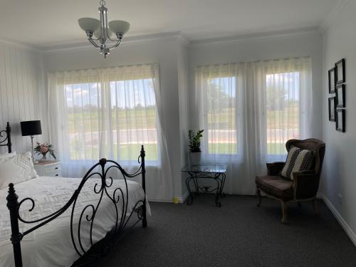 a bedroom with a bed and a chair and windows at Vineyard Views Rutherglen in Rutherglen