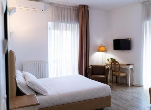 Habitación de hotel con cama, silla y escritorio. en Residence Le Vie del Centro, en Matera