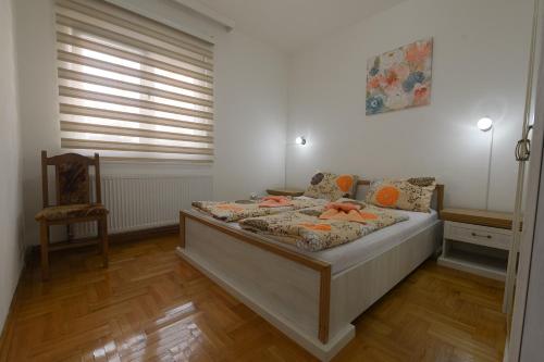a bedroom with a bed in a room with a chair at Capitol Apartmani in Vrnjačka Banja