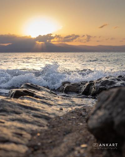 a sunset over the ocean with rocks in the water at Aegean Feelings in Piso Livadi