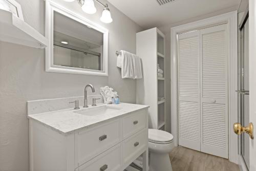 a white bathroom with a sink and a toilet at East Beach Villa Unit 204 in East End