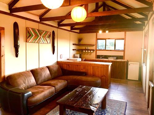 a living room with a leather couch and a table at Pura Vida Forest Cabin in Witelsbos