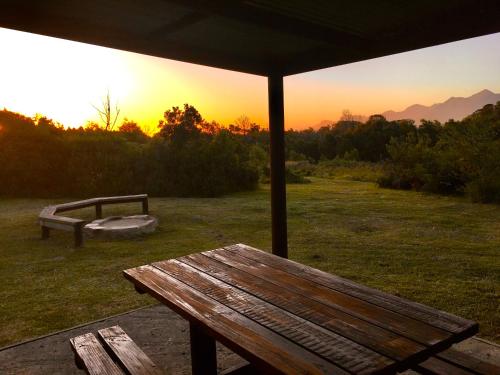 a picnic table in a field with a sunset in the background at Pura Vida Forest Cabin in Witelsbos