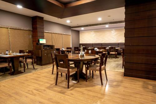 a dining room with tables and chairs and a screen at Hotel Halez in Chennai