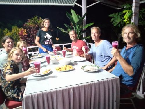 un grupo de personas sentadas alrededor de una mesa con comida en Pondok Oma III, en Lasikin