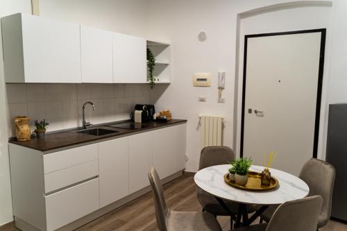 una cocina con armarios blancos y una mesa con sillas. en Residence Le Vie del Centro, en Matera