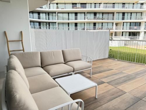 Un sofá y una silla en un balcón con un edificio en Apartamento La Calma a 2 pasos de la playa, en Denia