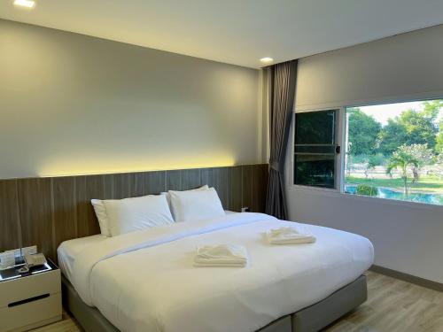 a bedroom with a large white bed with a window at Bandu Resort in Ban Du