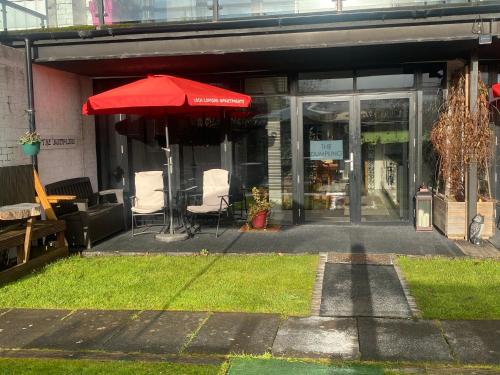 a store front with a red umbrella and chairs at loch lomond apartments in Alexandria