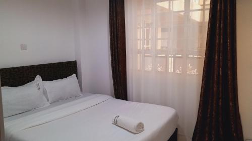 a bedroom with a white bed and a window at Hotfoot Homestay in Nanyuki