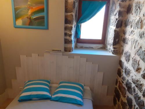 een bed met twee blauwe en witte kussens in een kamer bij Gîte le MAGNAN, 55 m2, havre de paix, terrasse, jardin, piscine chauffée, sud Ardèche in Joyeuse