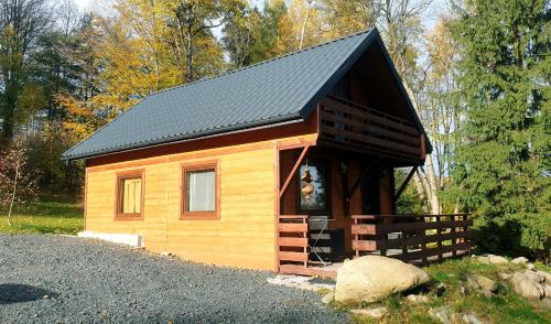 a small wooden cabin with a black roof at Omszałe Głazy in Zachełmie
