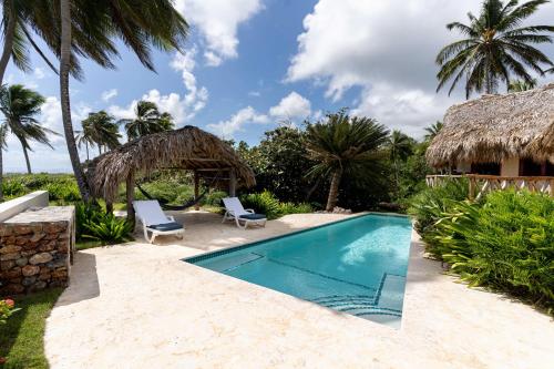 a swimming pool with two chairs and a resort at Villa Punta Coral in Las Galeras